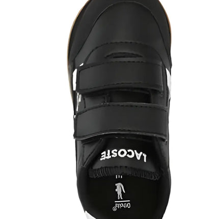 lacoste partner piste black sneakers shown beside travel gear and sunglasses